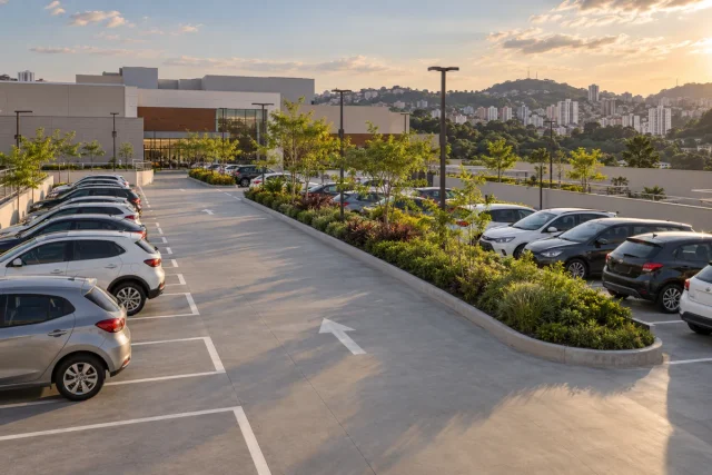 Estacionamento de centro comercial com vagas, faixa de circulação e ilha ajardinada.