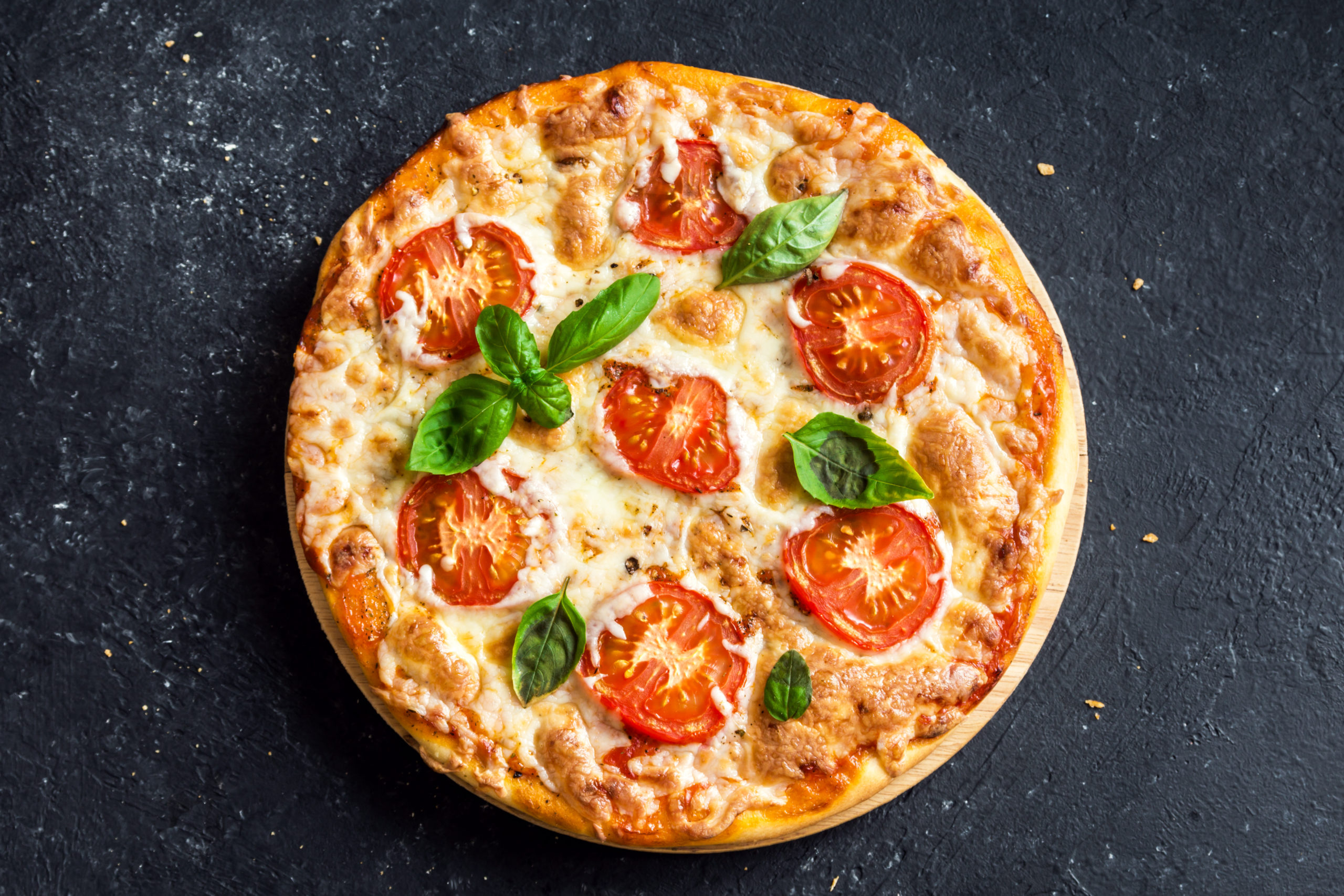 Pizza Margherita on black stone background, top view. Pizza Margarita with Tomatoes, Basil and Mozzarella Cheese close up.