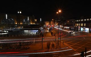 Uma rua da cidade à noite com sinais de trânsito e edifícios ao fundo e um poste de luz no primeiro plano com um sinal de trânsito no meio, (uma foto do tipo tilt shift: 0,198).