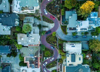 Uma estrada serpenteando por um bairro com casas e carros ao seu redor e uma rua com carros em ambos os lados e casas em ambos os lados. (uma foto de estoque: 0,279)