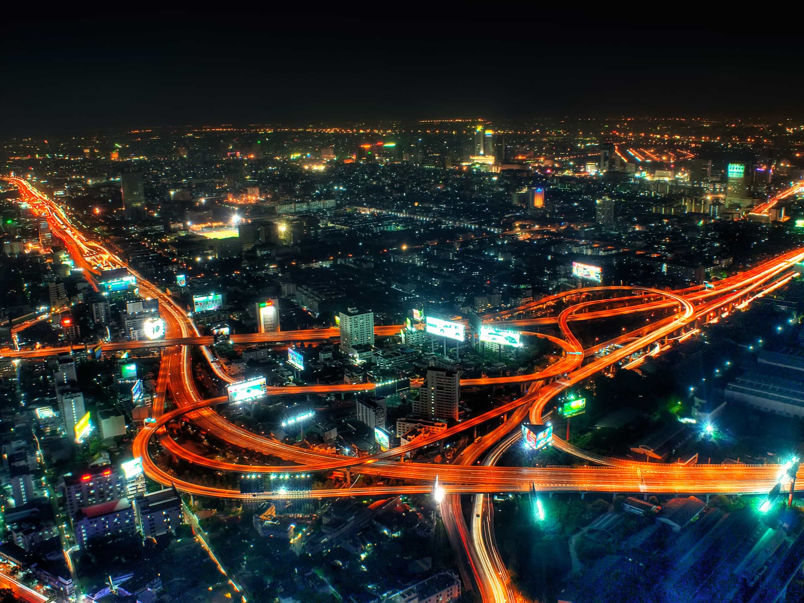 Uma cidade à noite com muito tráfego e luzes nas suas ruas e estradas e as luzes das ruas estão acesas e uma rua da cidade está iluminada, (uma foto microscópica: 0,156).