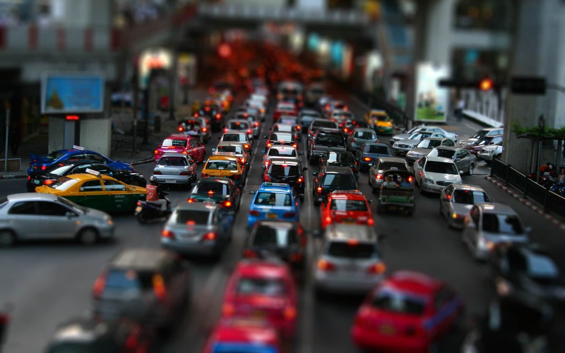 Uma rua movimentada da cidade cheia de muito tráfego e muitos semáforos à beira da estrada com um prédio ao fundo e um semáforo na rua, (uma foto com efeito tilt shift: 0,977).