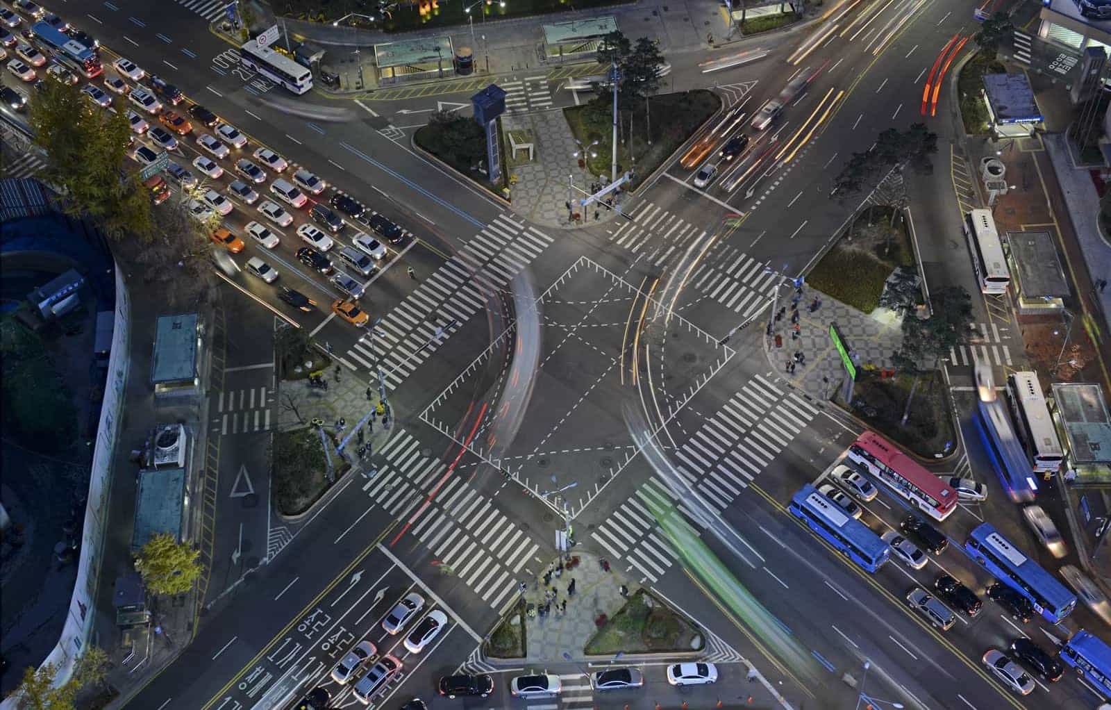 Uma vista aérea de uma interseção movimentada com carros e ônibus à noite, vista de cima, olhando para baixo na interseção e no tráfego da interseção. (uma renderização digital: 0,434)