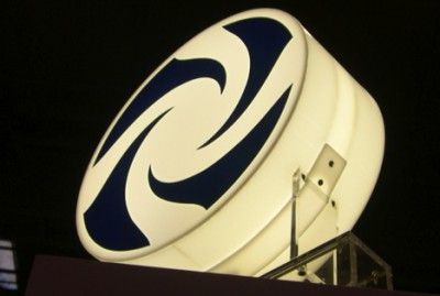 Um grande letreiro que está no topo de um prédio à noite, com um fundo escuro e um céu negro atrás, com um design circular branco e azul, (uma representação de computador: 0,314).