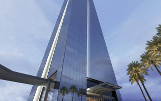 Um prédio muito alto com uma torre muito alta ao lado, refletindo na água ao entardecer, com palmeiras em primeiro plano. (uma renderização digital: 0,753)