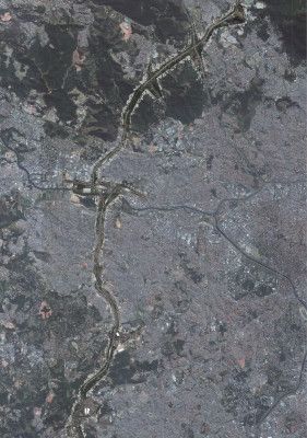 Uma imagem de satélite de uma estrada no meio de uma cidade com um rio correndo por ela e uma estrada cortando o centro da cidade, (um quebra-cabeça: 0,196).