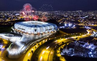 Um estádio com fogos de artifício no céu e um grande prédio com uma cúpula em cima à noite, com a linha do horizonte da cidade ao fundo. (uma representação digital: 0,660)