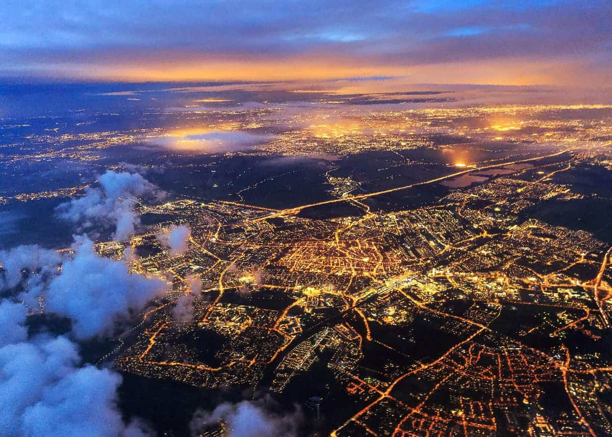 Uma vista de uma cidade a partir de um avião durante a noite, com nuvens e luzes no chão e as luzes da cidade ao longe, (uma foto microscópica: 0,178).