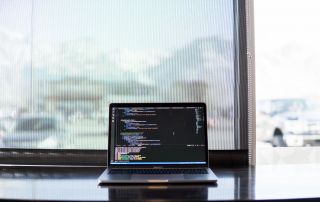 Um computador portátil sentado em cima de uma mesa ao lado de uma janela com carros do lado de fora e uma parapeito da janela atrás dele com um carro. (uma foto de estoque: 0,350)