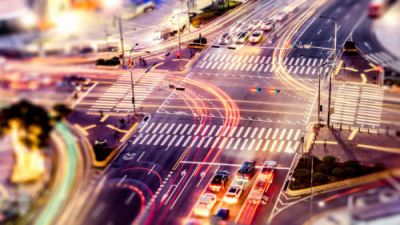 Uma imagem borrada de uma rua movimentada da cidade durante a noite com semáforos e placas de rua na rua e um semáforo na esquina, (uma foto tilt shift: 0,369)