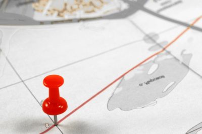 Um botão vermelho de pressão em um mapa da cidade com uma linha vermelha passando por ele e uma linha vermelha passando pelo meio do mapa. (captura de tela: 0,165)